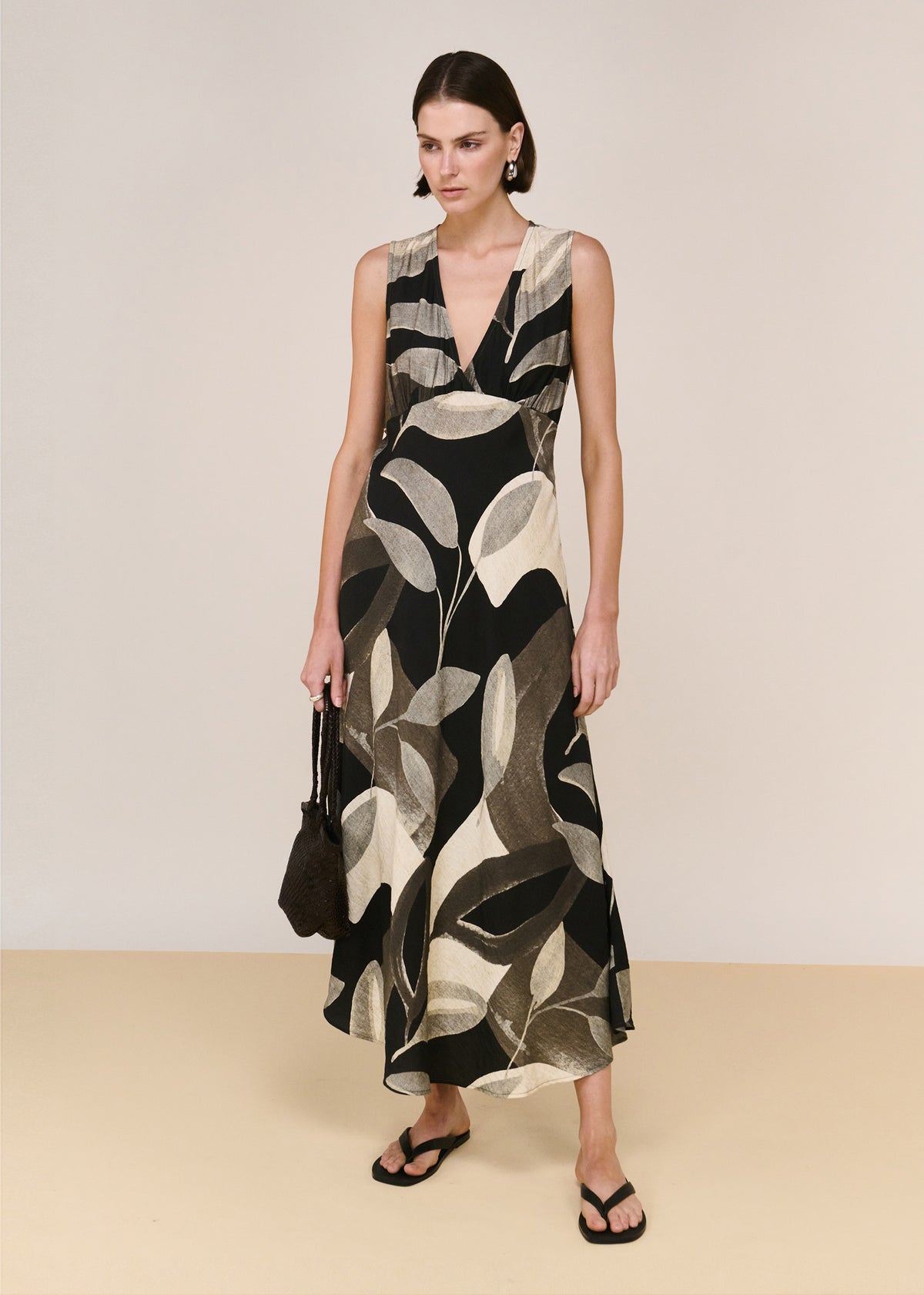 Model wearing Dark Leaf Bias Midi Dress with a midi length and an exclusive Dark Leaf Garden print.