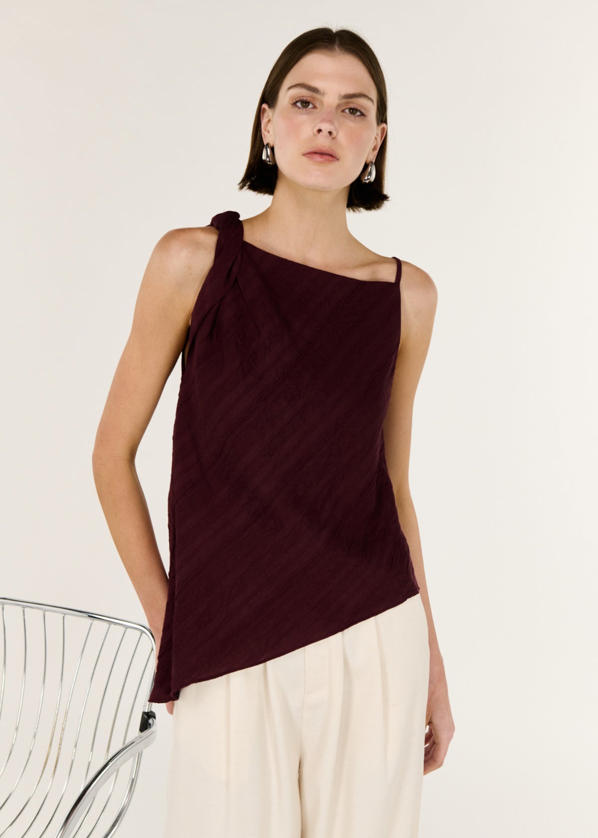 Close-up of the Dark Red Textured Asymmetrical Twist Top, showing an asymmetric neckline with twist shoulder detail and a sleeveless cut.