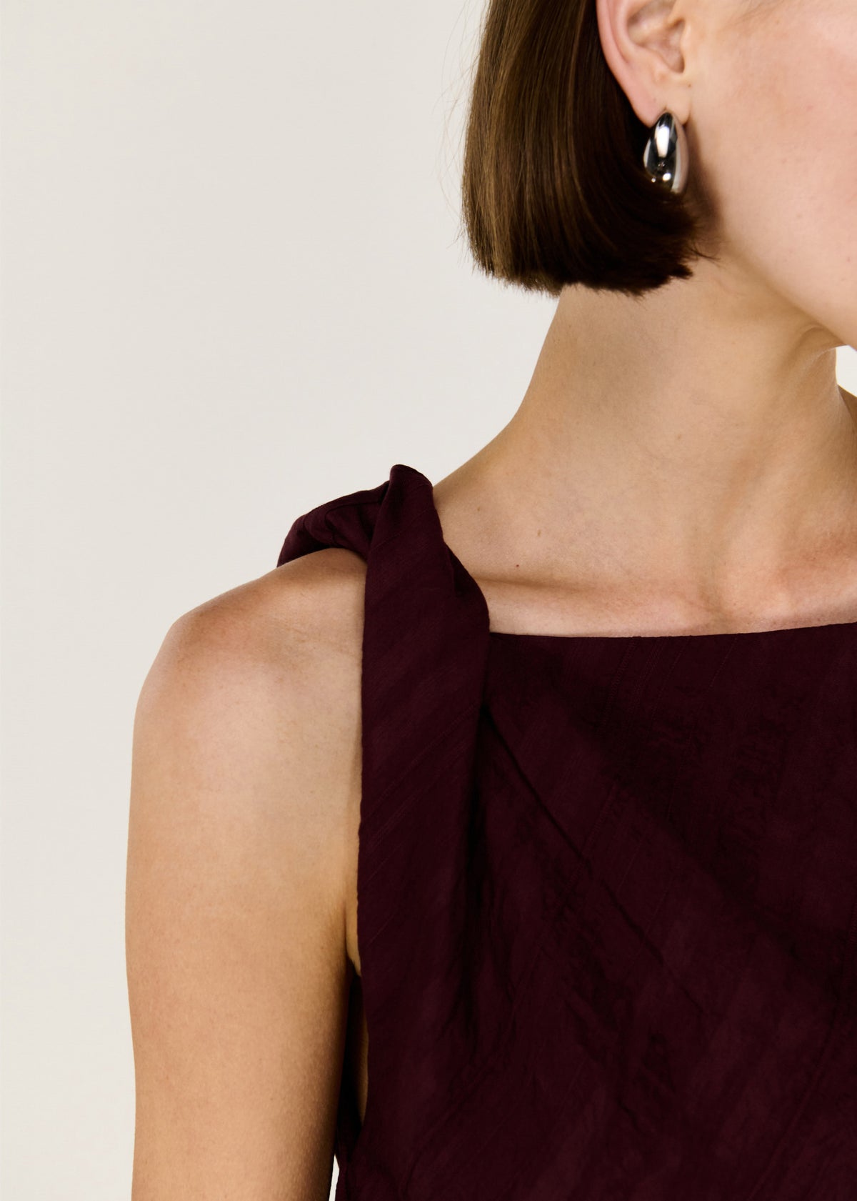 Close-up detail of the Dark Red Textured Asymmetrical Twist Top, showing twisted shoulder.