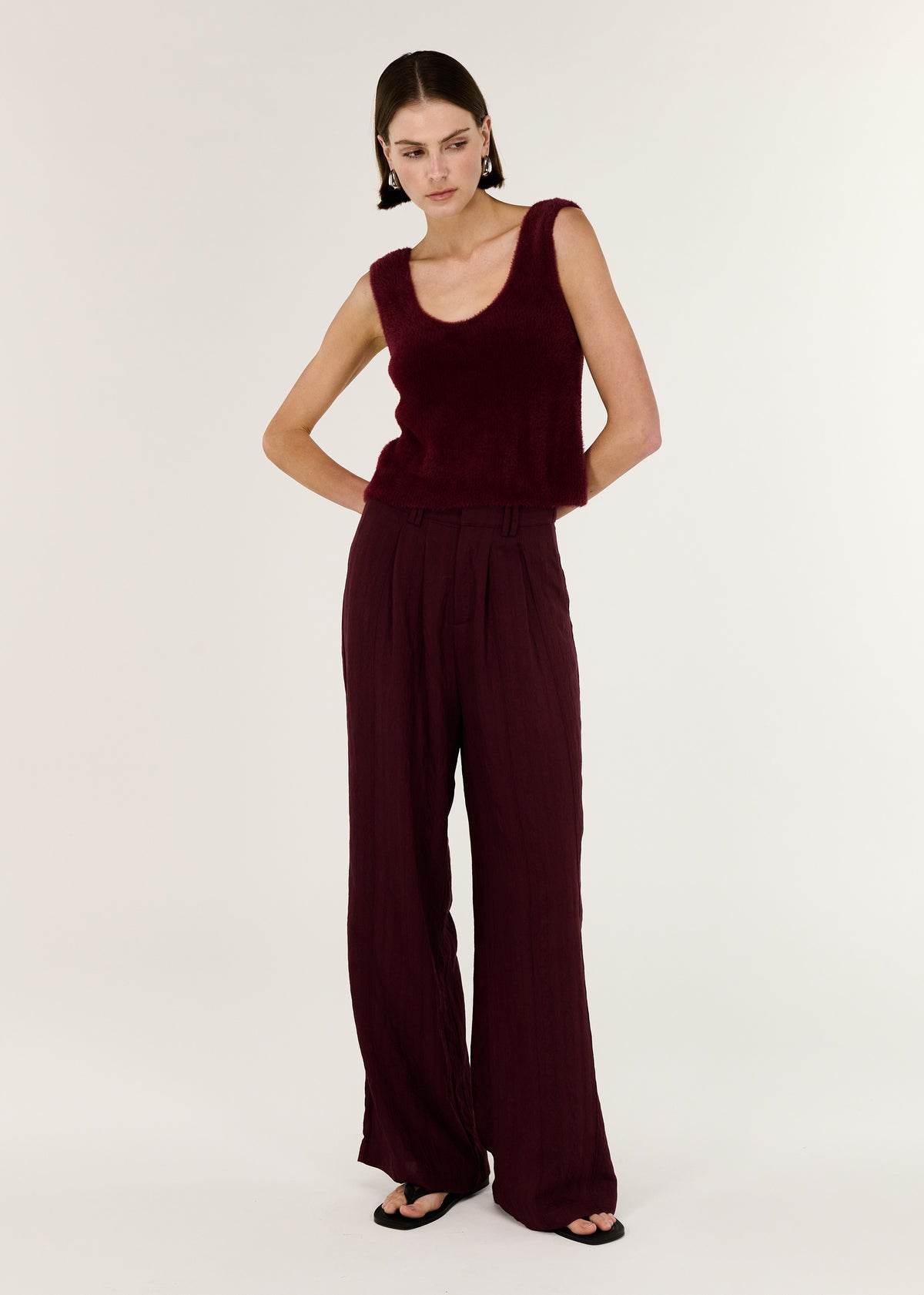 Model wearing Deep Red Plush Cotton Knit Tank with a scoop neckline and a relaxed fit, turned to the side.