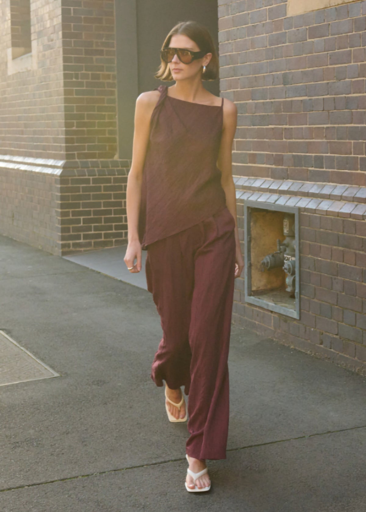 Model wearing Deep Red Textured Wide-Leg Pant with a soft front pleating and a lightweight feel, turned to the side.