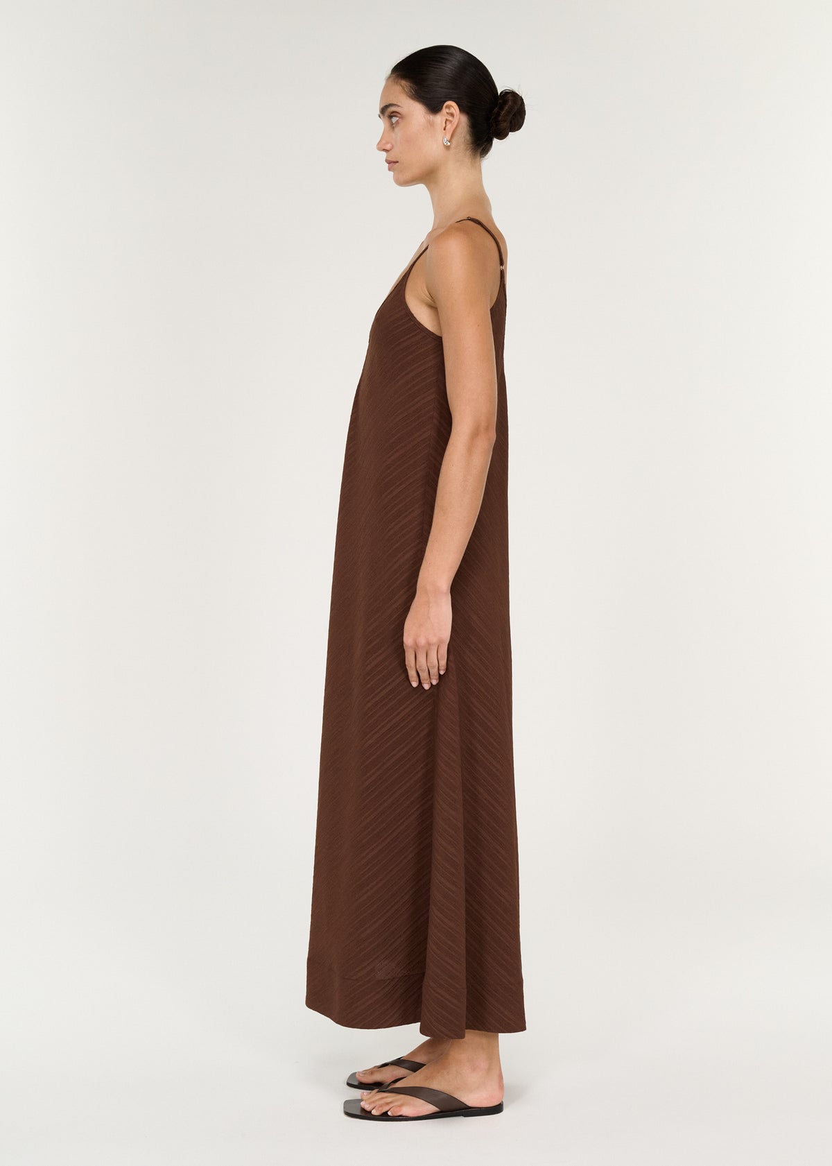 Side view of a woman wearing a Textured Maxi Dress in Chocolate with adjustable straps and a full, flowing silhouette.