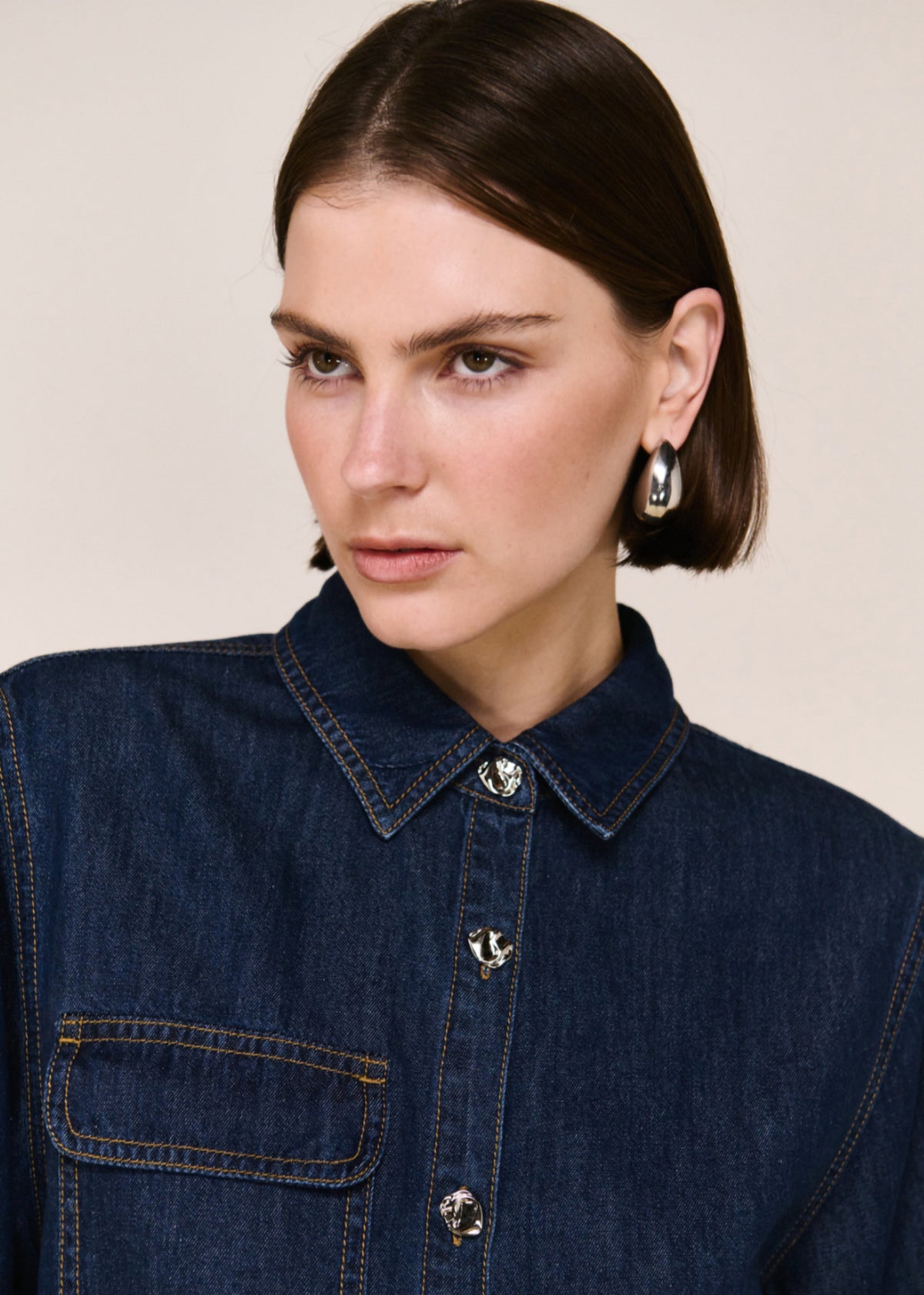 Close-up detail of the Denim Cropped Short-Sleeve Shirt, showing chest pocket and buttons.