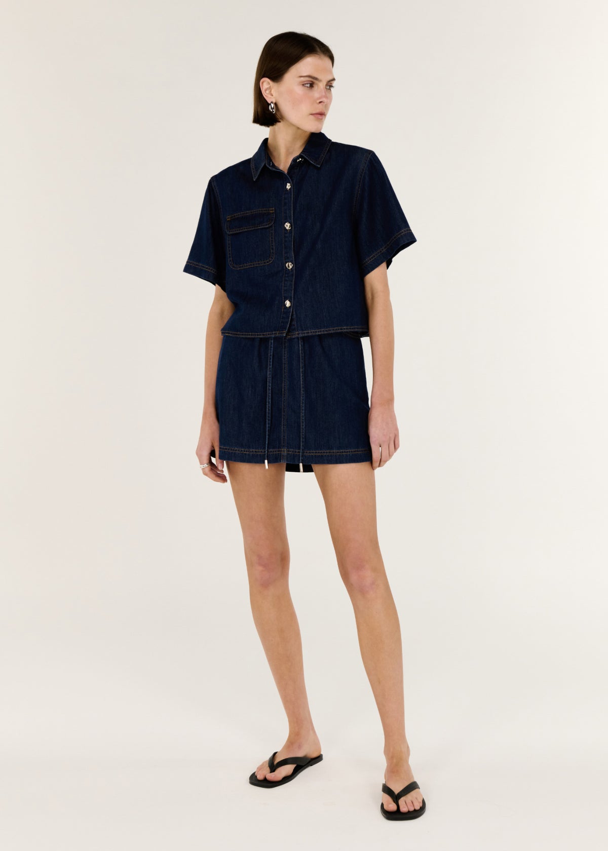 Model wearing Denim Elasticated Mini Skirt with a structured indigo denim and a high-rise fit.