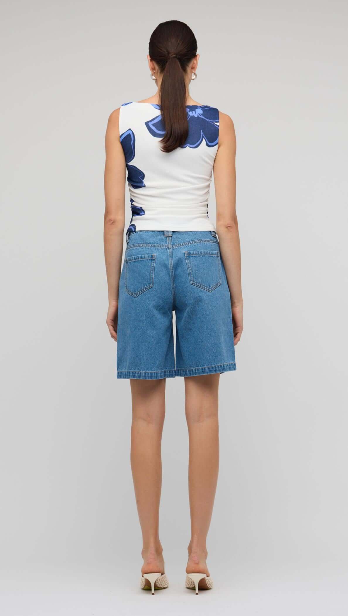 Denim Mid-Rise Shorts styled with a floral top, showcasing a relaxed fit and classic five-pocket design from the back.