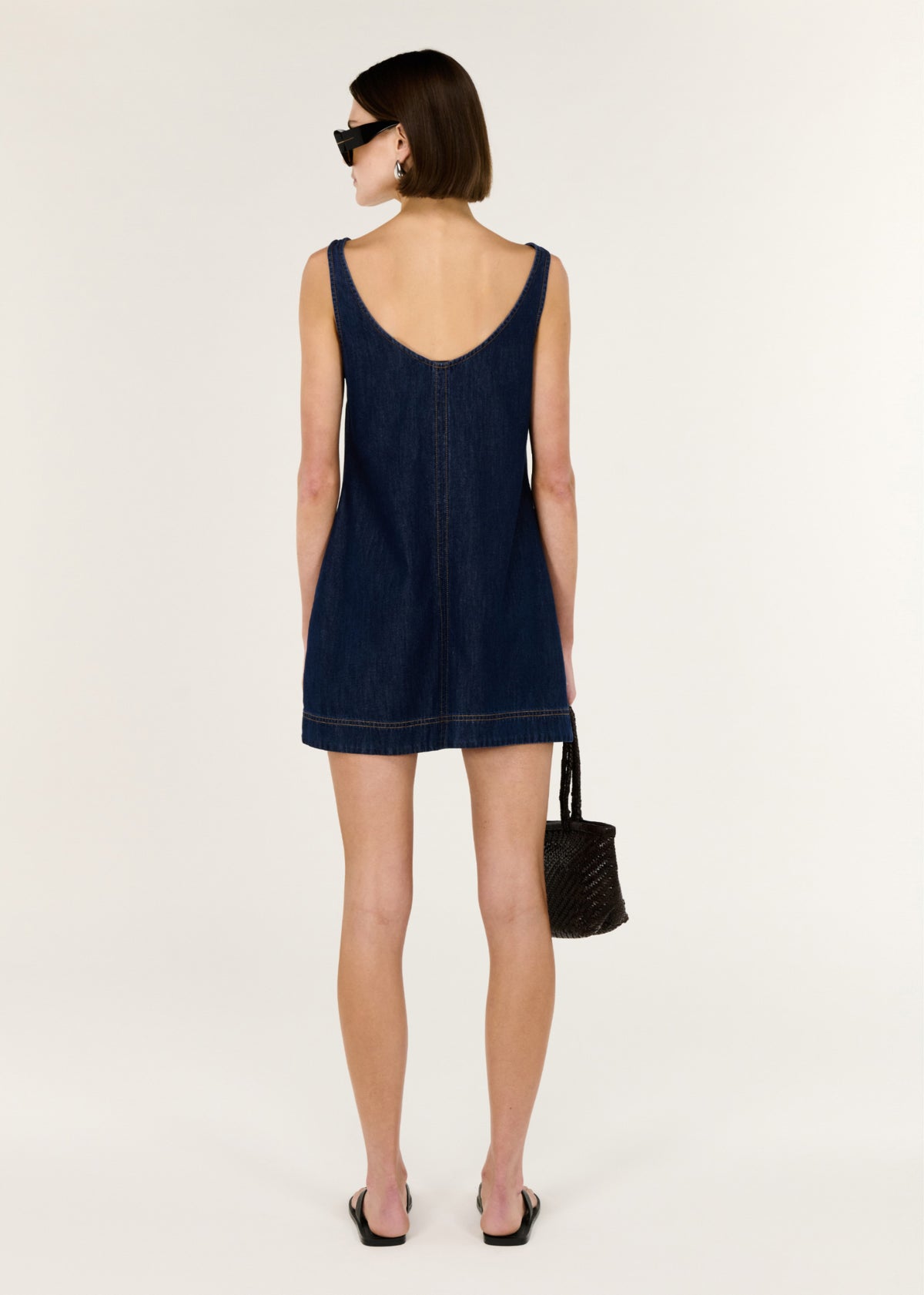 Back view of the Denim Mini Dress with Scoop Back, showing a scoop back neckline and a sleeveless denim mini dress Clean A-line silhouette.