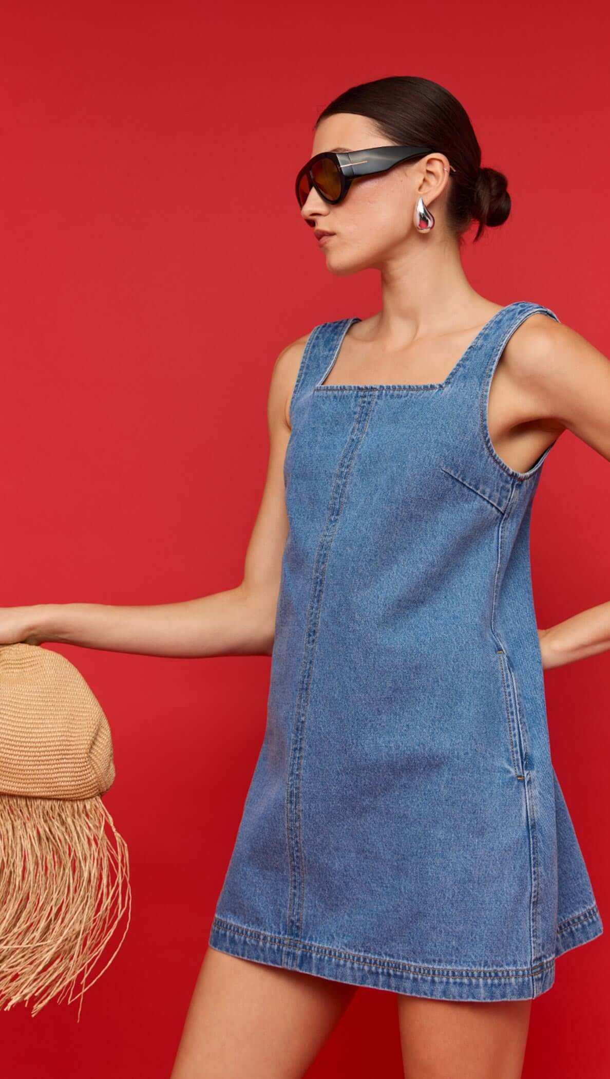 Denim Square Neck Mini Dress modeled against a vibrant red background, showcasing its relaxed A-line silhouette.
