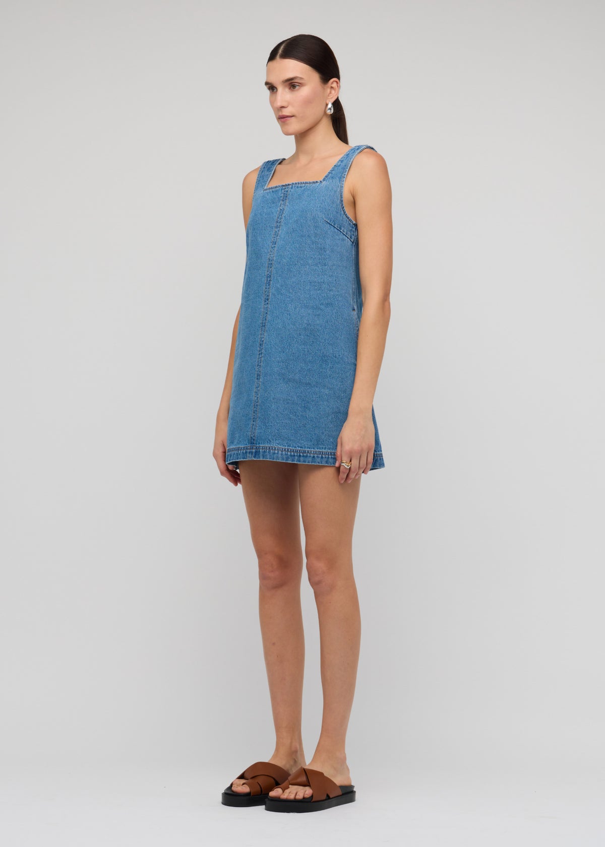 Angled view of the Denim Square Neck Mini Dress with a sleeveless cut and a relaxed A-line fit.