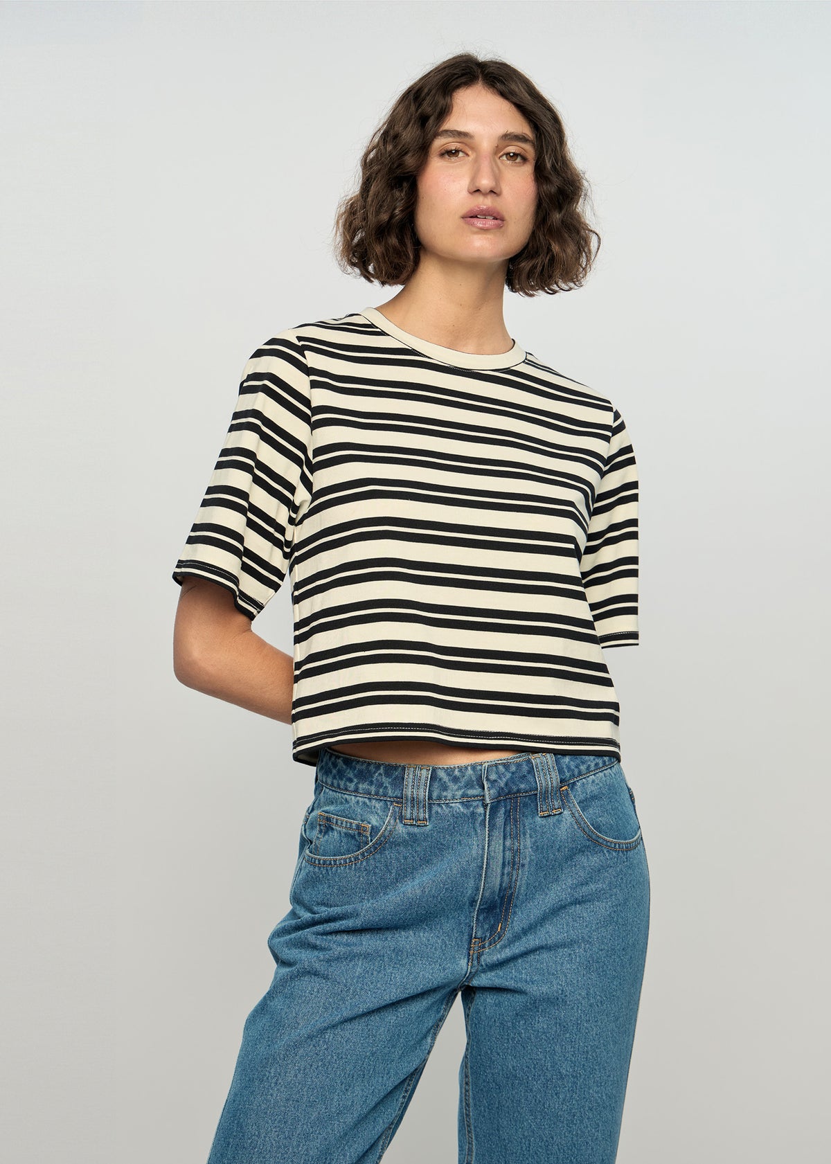 Model wearing Elara Crop Tee with a black and ivory stripe pattern.