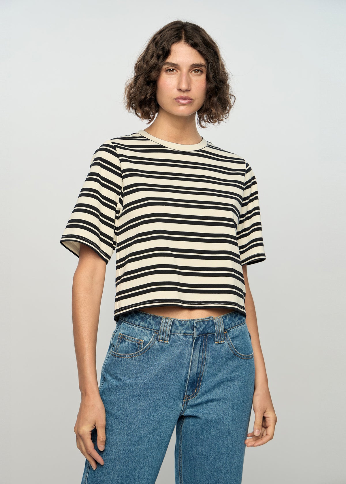 Model wearing Elara Crop Tee, showing a black and ivory stripe pattern.
