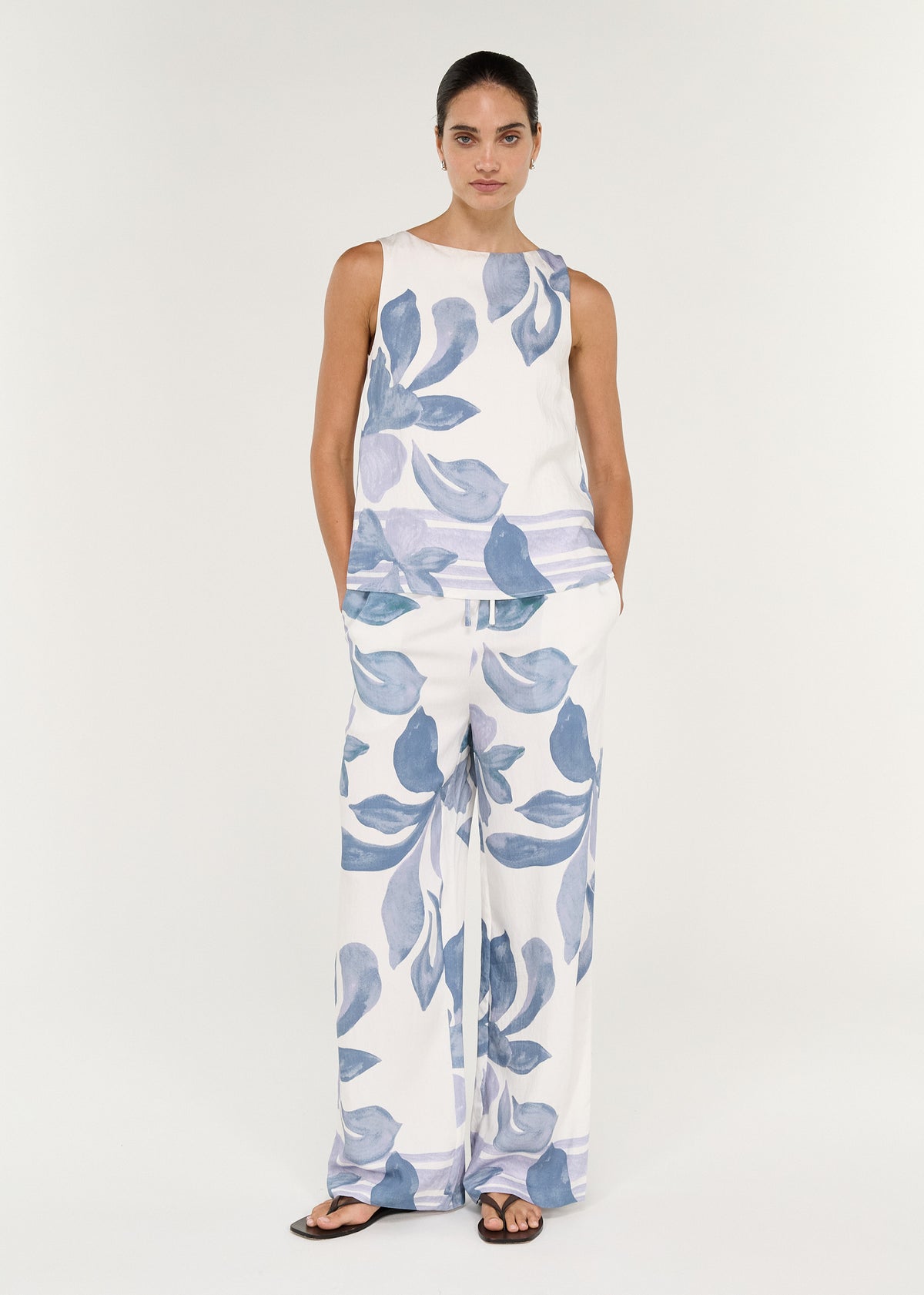 Model wearing Boatneck Sleeveless Top in Blue Floral paired with matching Elody pant, showcasing a relaxed fit and watercolor print.