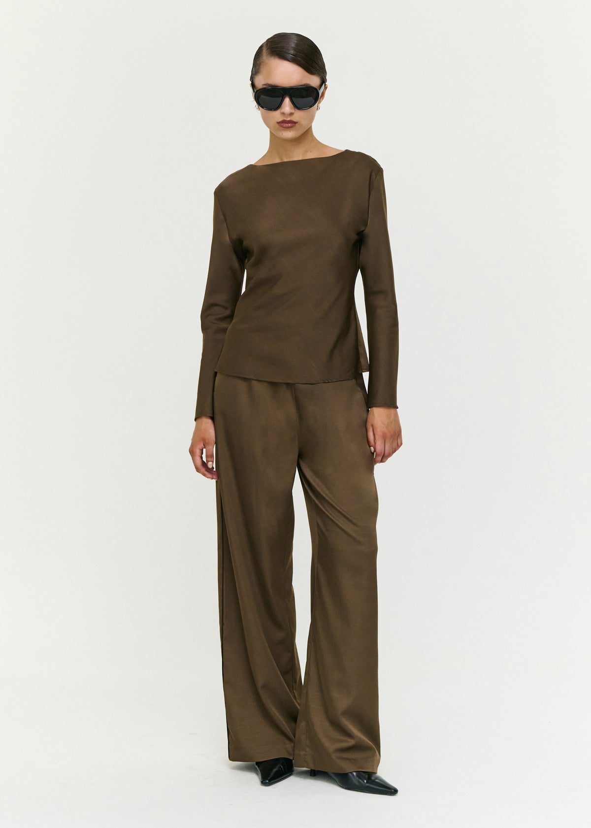 Model wearing Espresso Relaxed Cut Silky Pant, showing a mid rise fit and a full-length design.