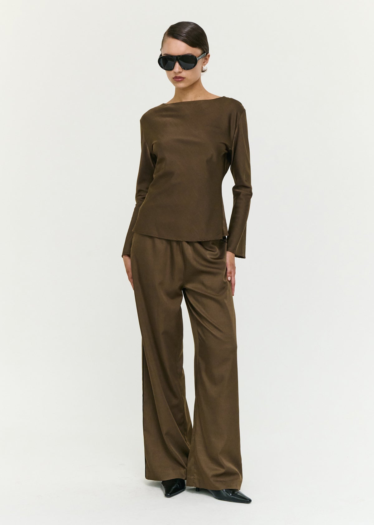 Model wearing Espresso Relaxed Cut Silky Pant with an elasticated waistband and a minimal detailing, turned to the side.