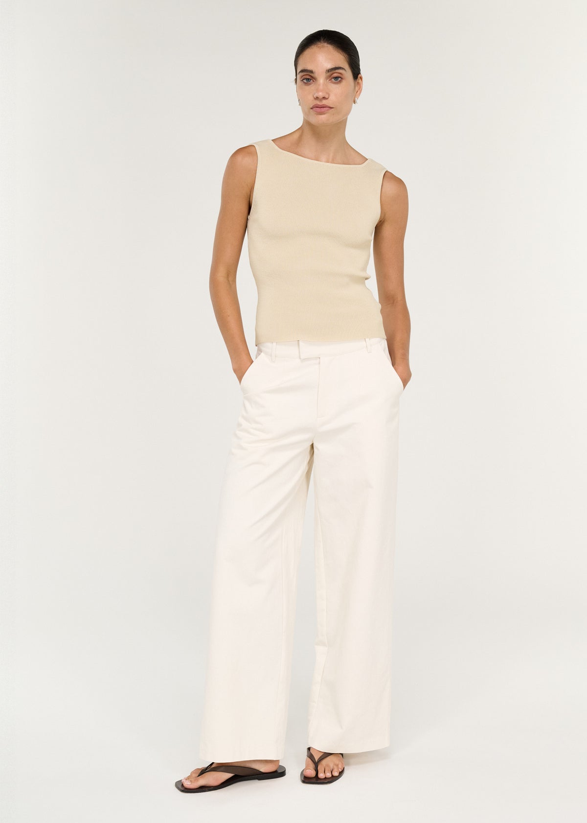 Model wearing Fine Rib Knit Reversible Tank in Ecru with a soft curved neckline and a fitted silhouette, turned to the side.