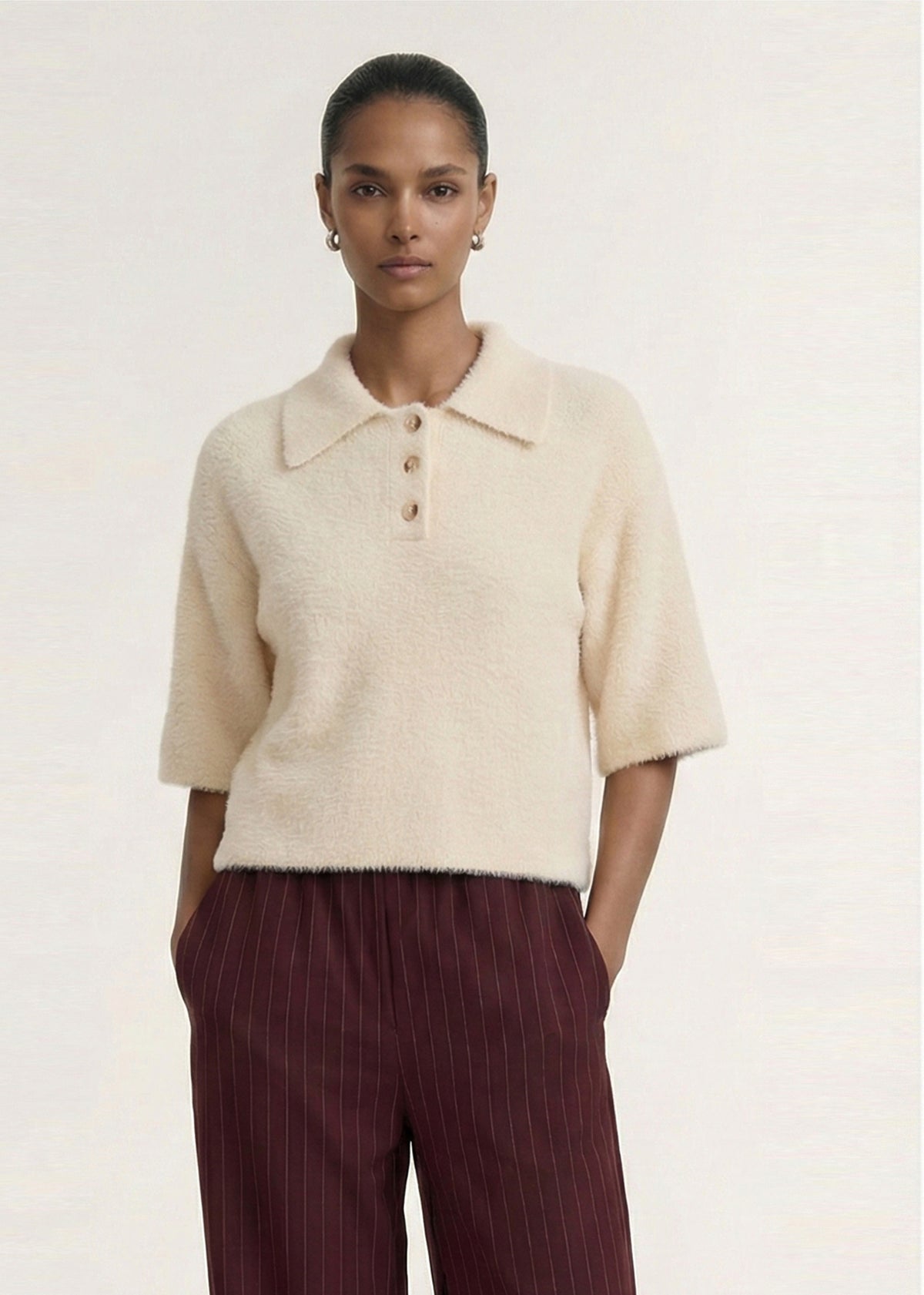 Model wearing Fluffy Knit Polo Top in Cream with a soft textured knit fabrication and a relaxed fit silhouette.