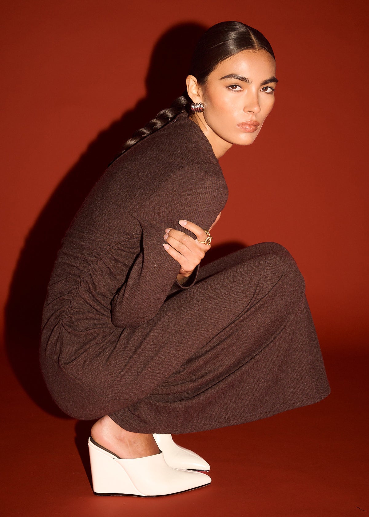 Model seated wearing Gather Detail Long Sleeve Jersey Midi Dress in Chocolate with long sleeves and a midi length.
