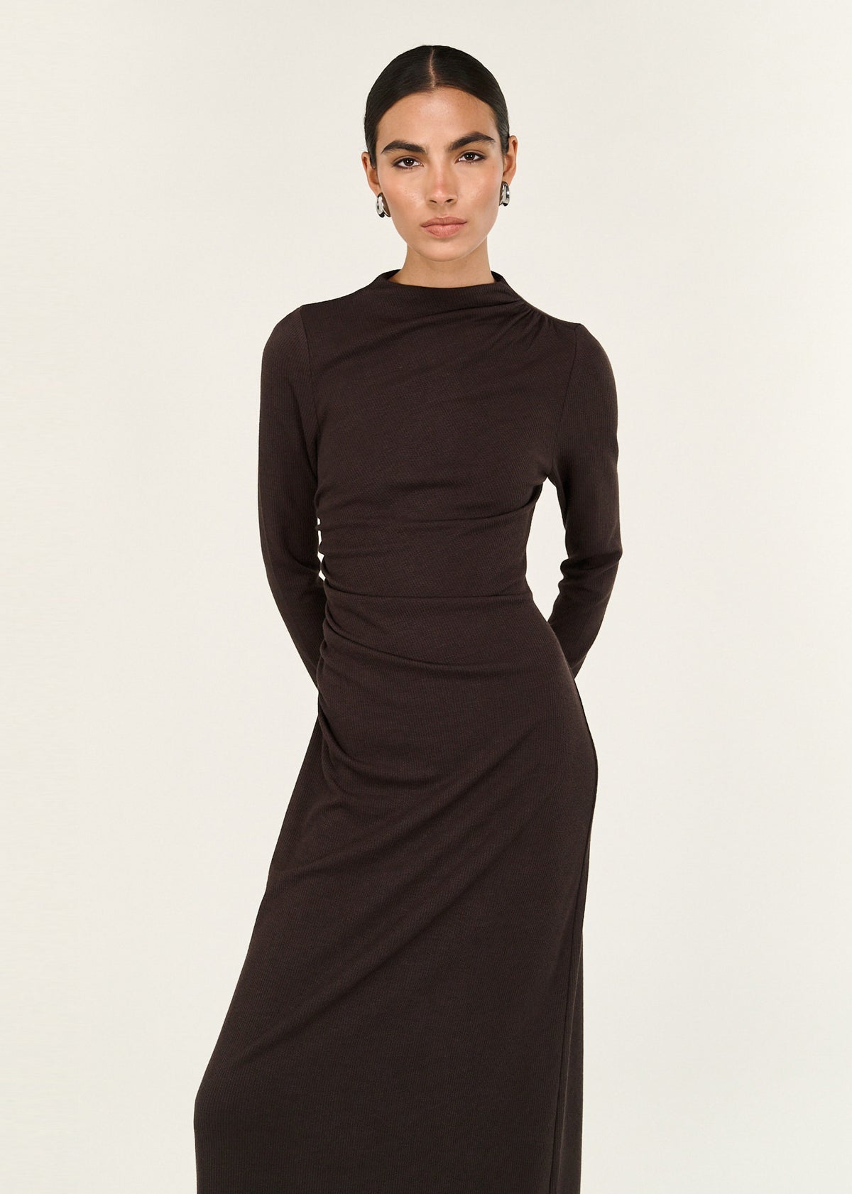Model wearing Gather Detail Long Sleeve Jersey Midi Dress in Chocolate with a high neckline and long sleeves, turned to the side.