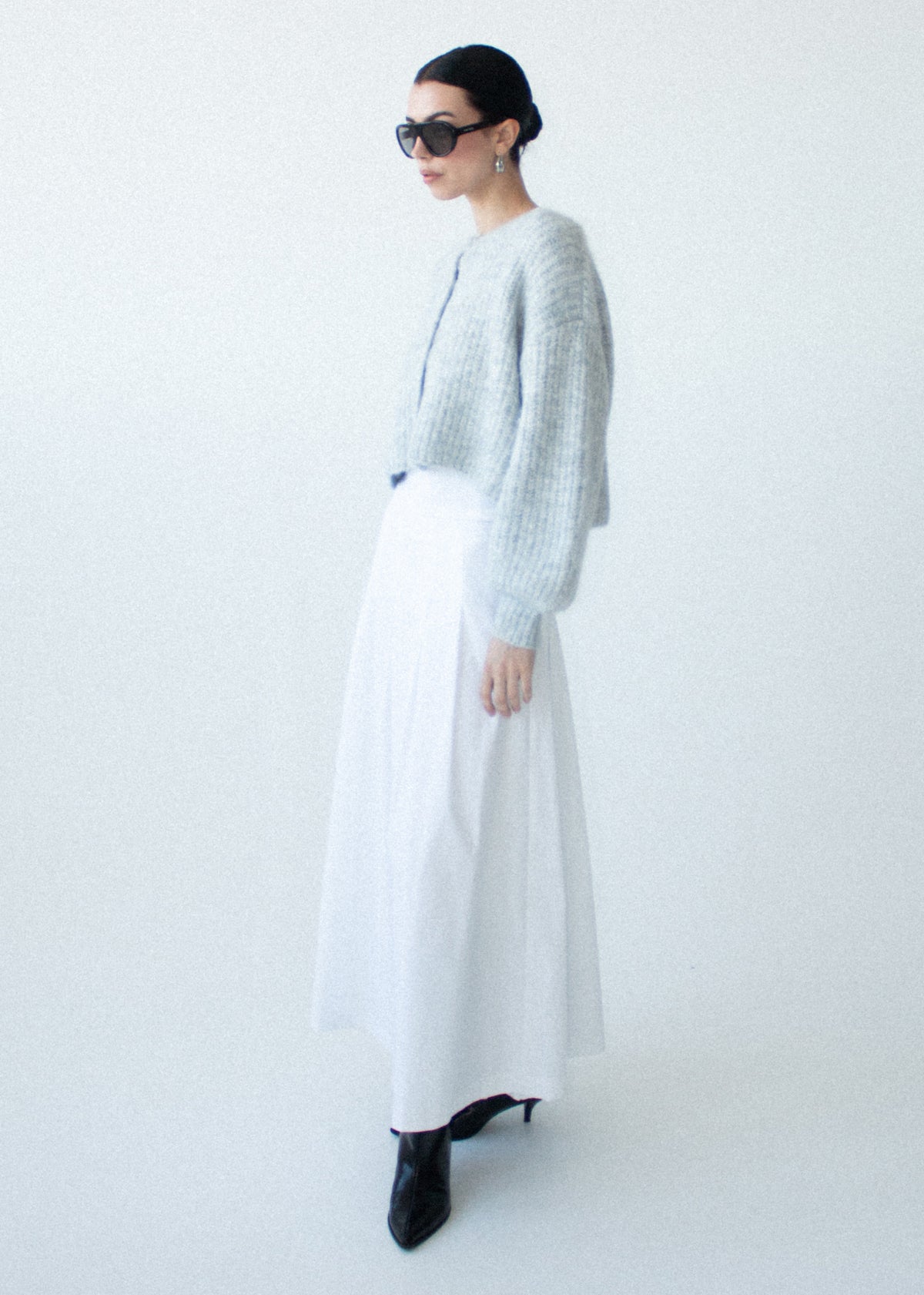 Model wearing Grey Marle Cropped Knit Cardigan with a soft, cosy feel and a crew neckline, photographed against a pale blue studio.