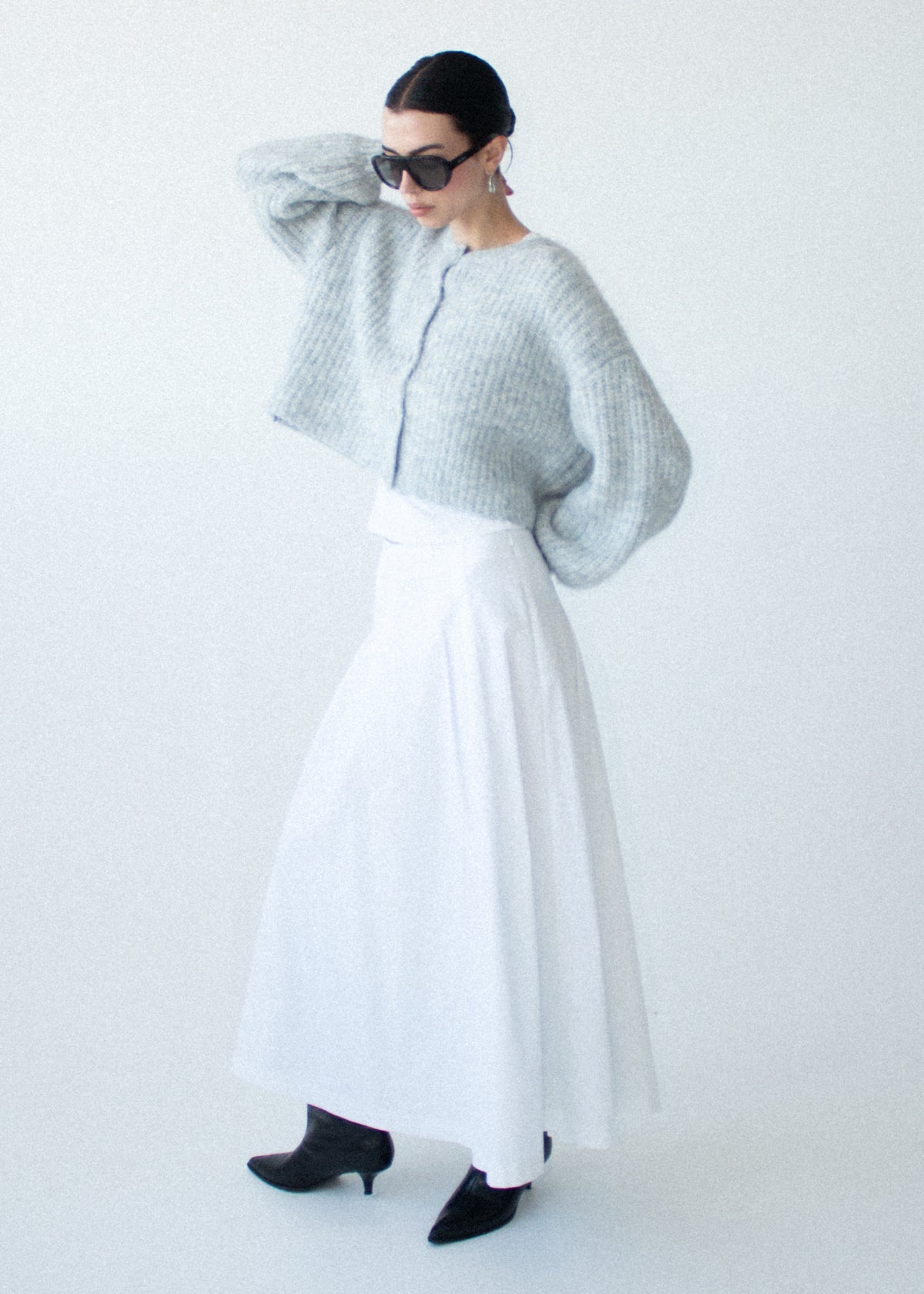 Model wearing Grey Marle Cropped Knit Cardigan with a button-through front and a cropped length, turned to the side.