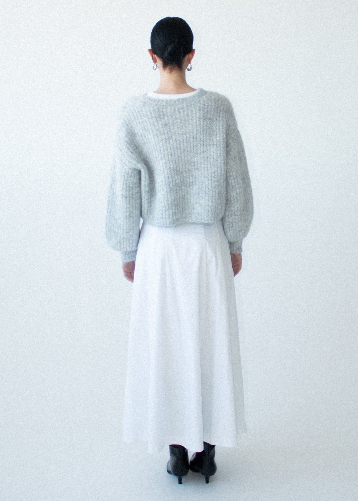 Back view of the Grey Marle Cropped Knit Cardigan with a button-through front and a crew neckline, photographed against a pale blue studio.