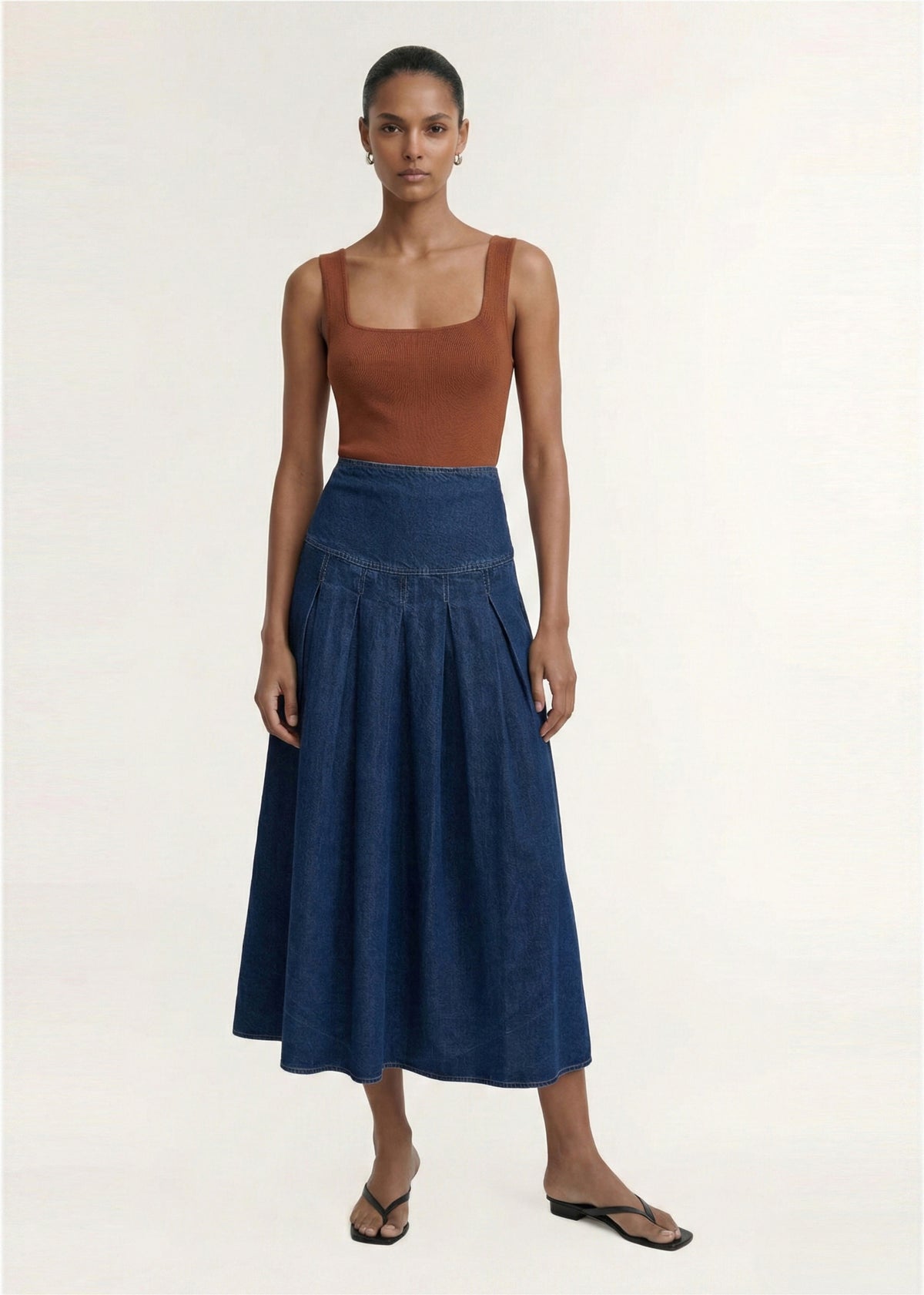 Model wearing Indigo Chambray Box Pleat Midi Skirt with a mid-weight denim fabrication and a fitted high waist.
