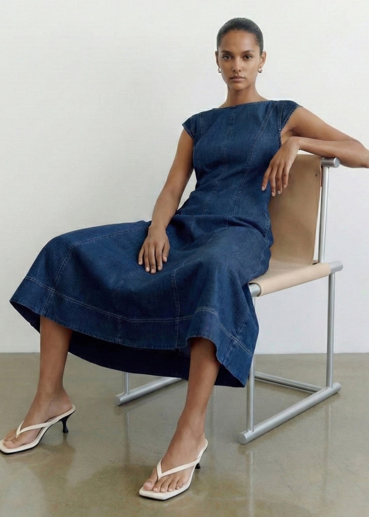 Model seated wearing Indigo Chambray Panelled Midi Dress with cap sleeves and a paneled seam detail.