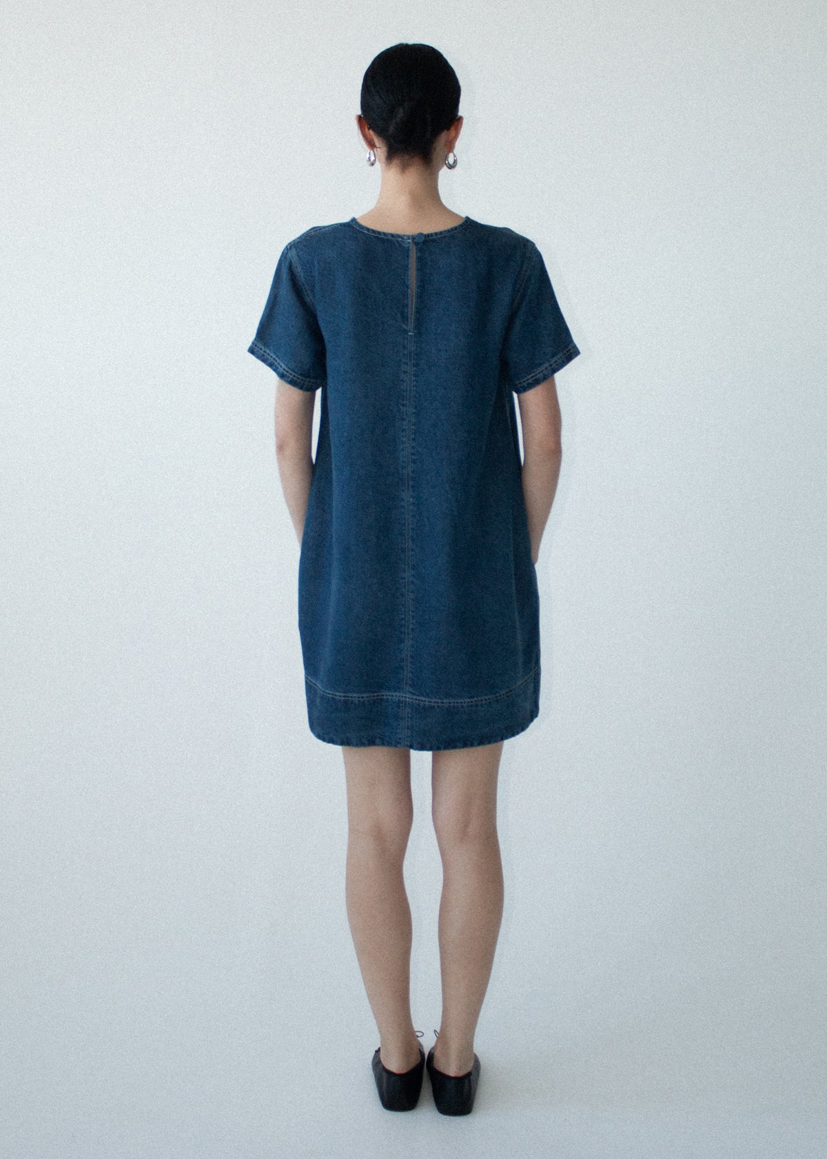 Back view of the Indigo Chambray Short Sleeve Mini Dress with a back zip closure and a mid-weight denim fabrication.