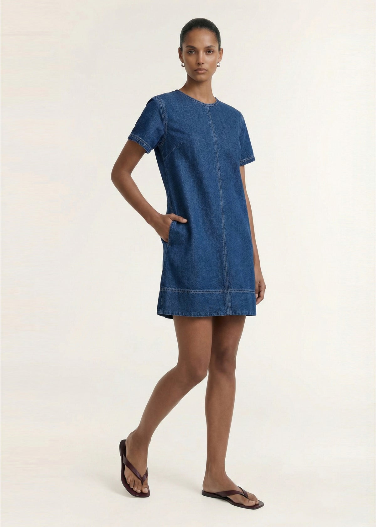Model wearing Indigo Chambray Short Sleeve Mini Dress with a round neckline and short sleeves, turned to the side.