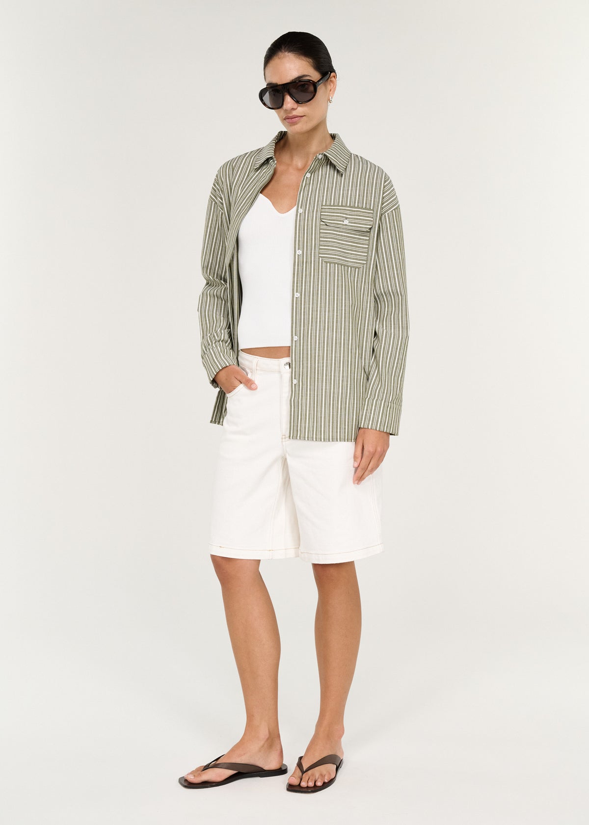 Model wearing Khaki Stripe Cotton Oversized Shirt with dropped shoulders and long sleeves with buttoned cuffs, turned to the side.