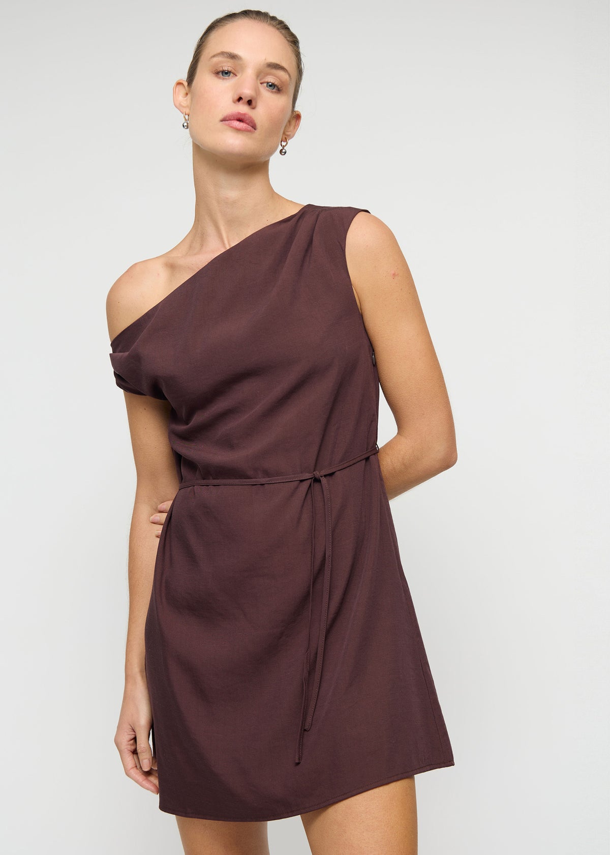 Close-up of the Linen Blend Chocolate Asymmetrical Mini Dress, showing a one-shoulder neckline and a statement self-tie bow detail.