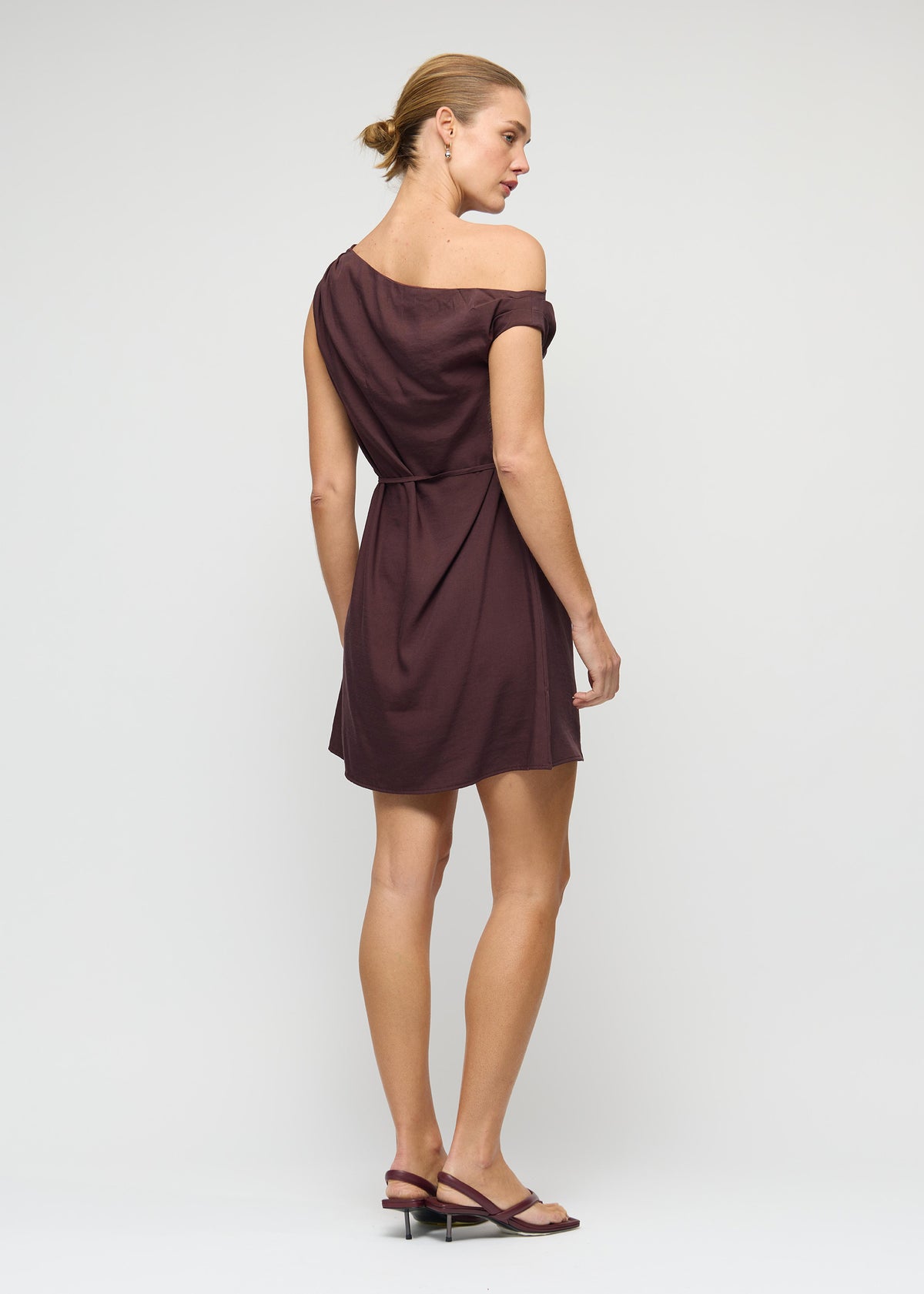 Model wearing Linen Blend Chocolate Asymmetrical Mini Dress with a relaxed A-line silhouette and a fully lined, turned to the side.