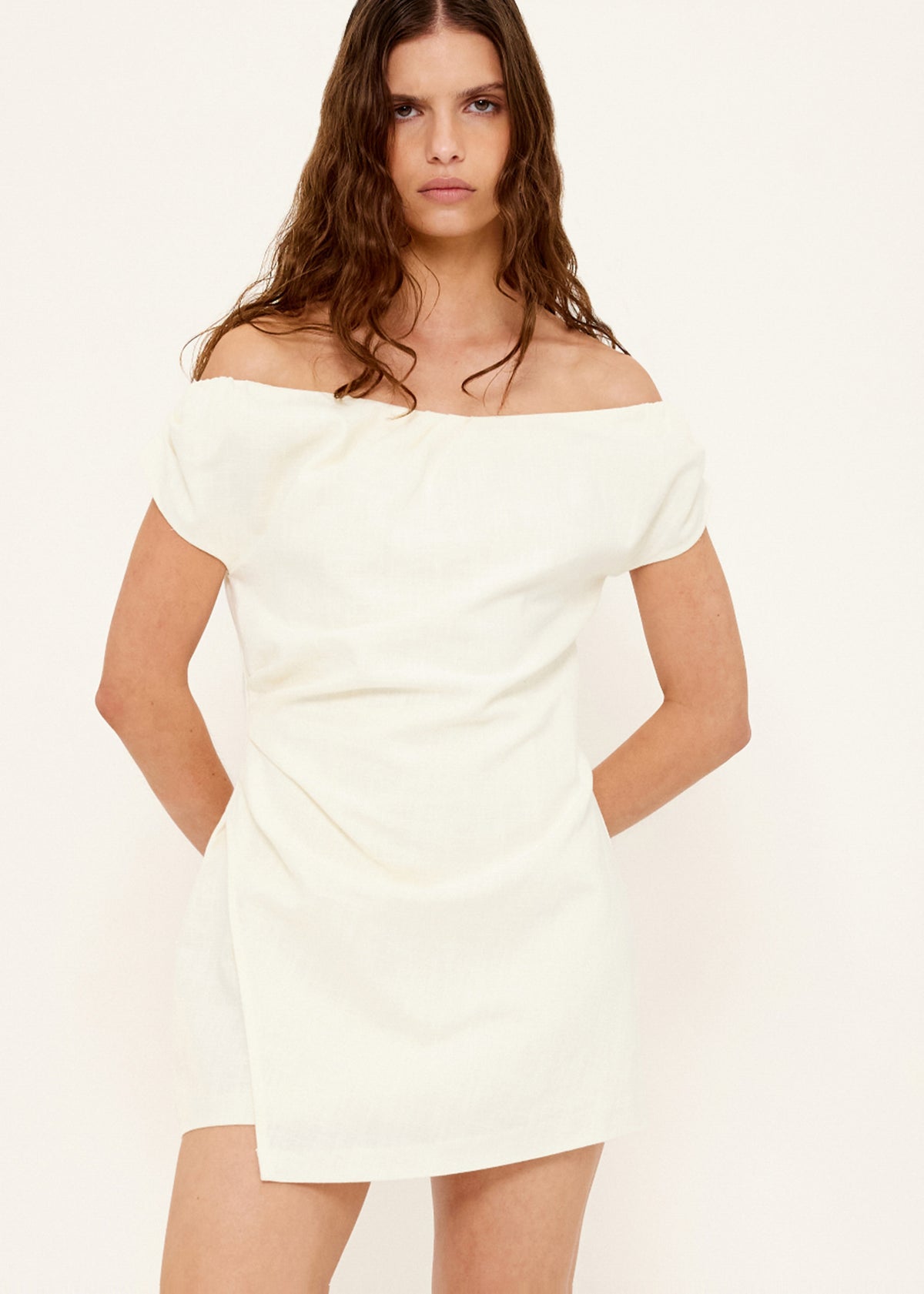 Model wearing Linen Blend White Off-Shoulder Mini Dress with an off-shoulder neckline and a short sleeves with subtle volume.