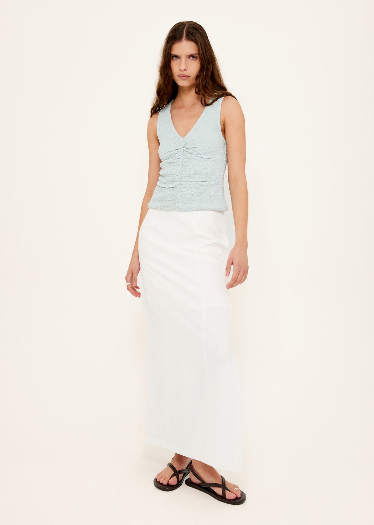 Model wearing Linen Cotton Blend White Midi Skirt with a high-waisted, straight cut midi silhouette and a side split.