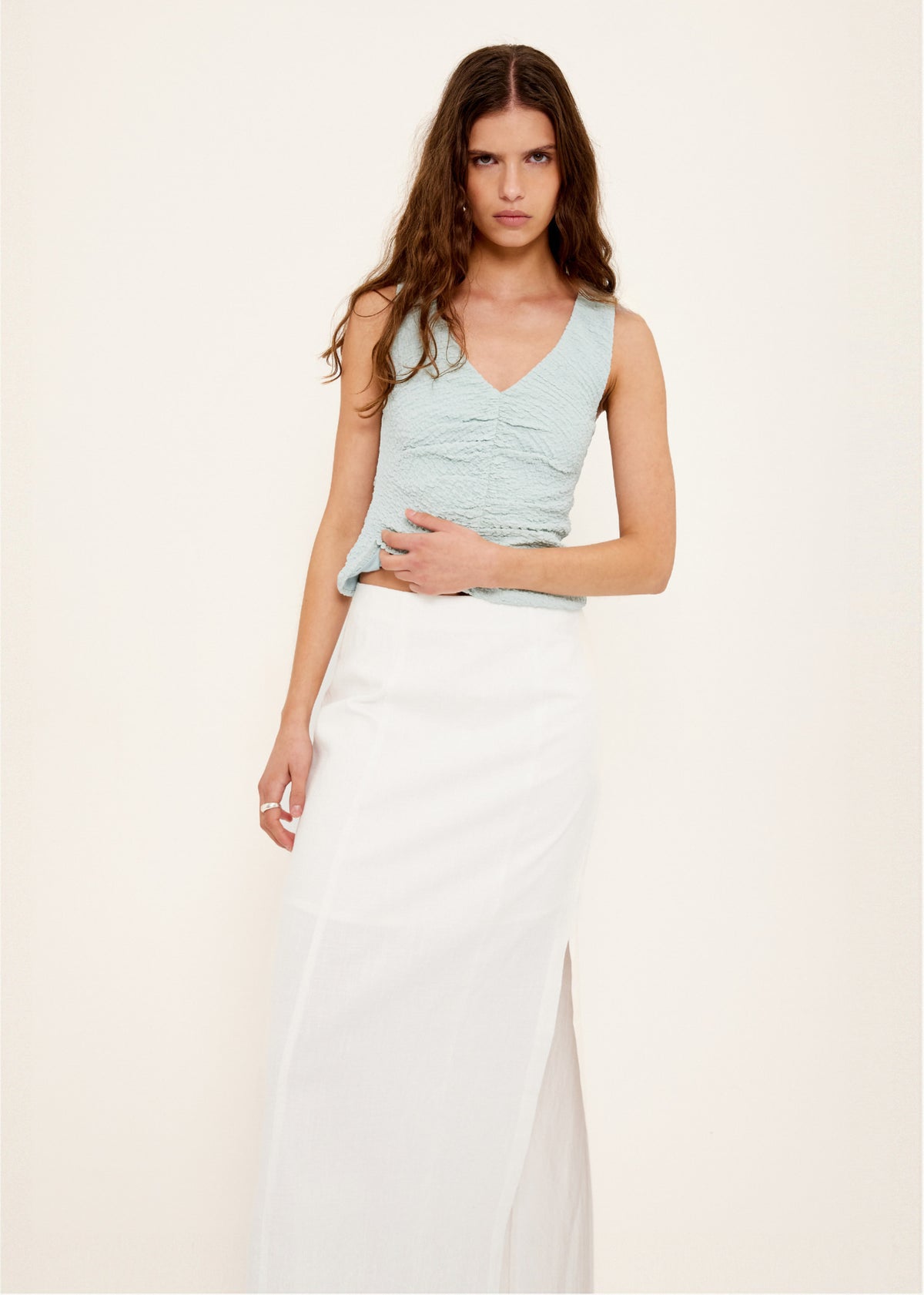 Model wearing Linen Cotton Blend White Midi Skirt with a crafted from a breathable linen-cotton blend, turned to the side.
