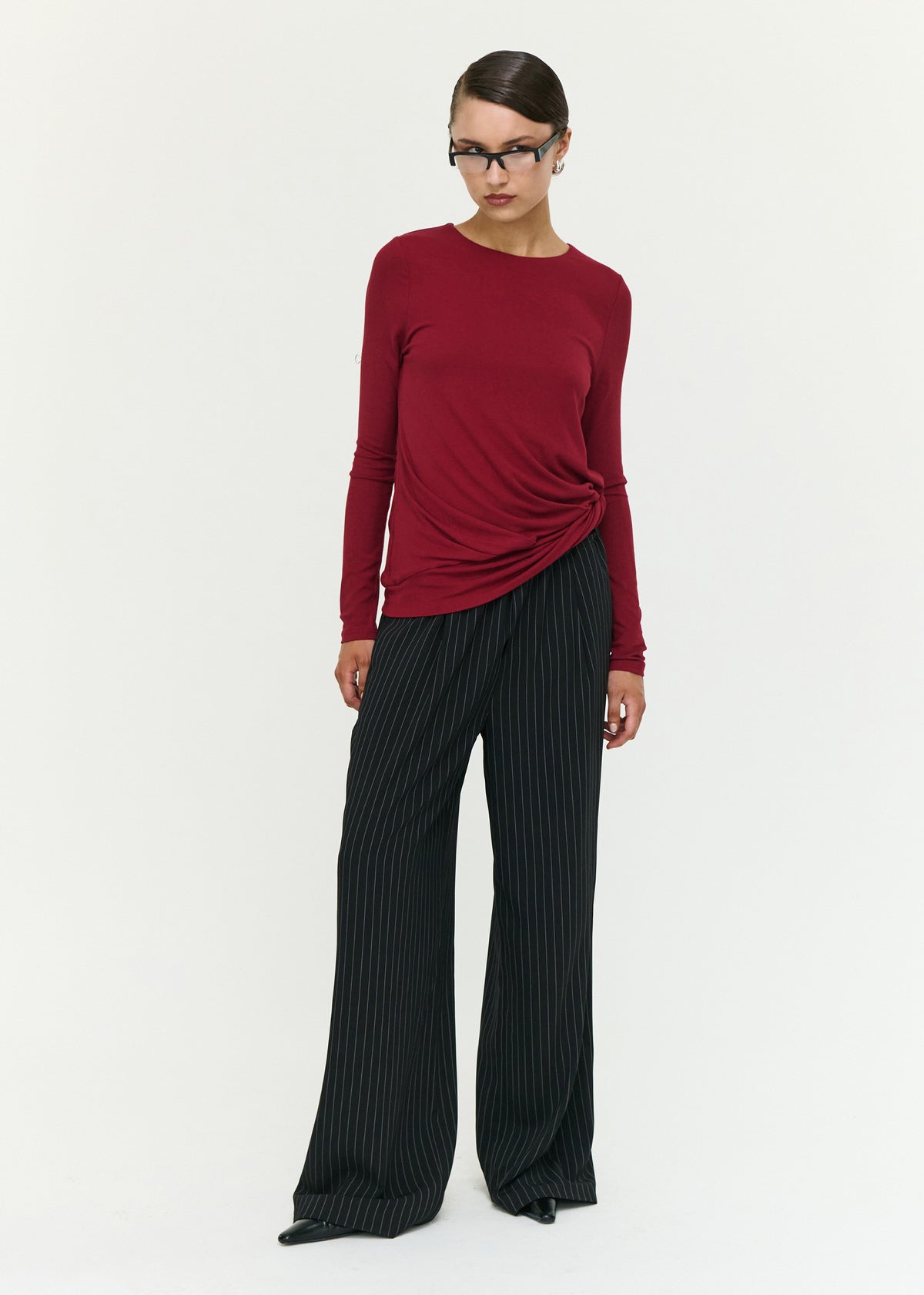 Model wearing Long Sleeve Jersey Twist Top in Merlot, showing a twist detail at hem and a lightweight feel.