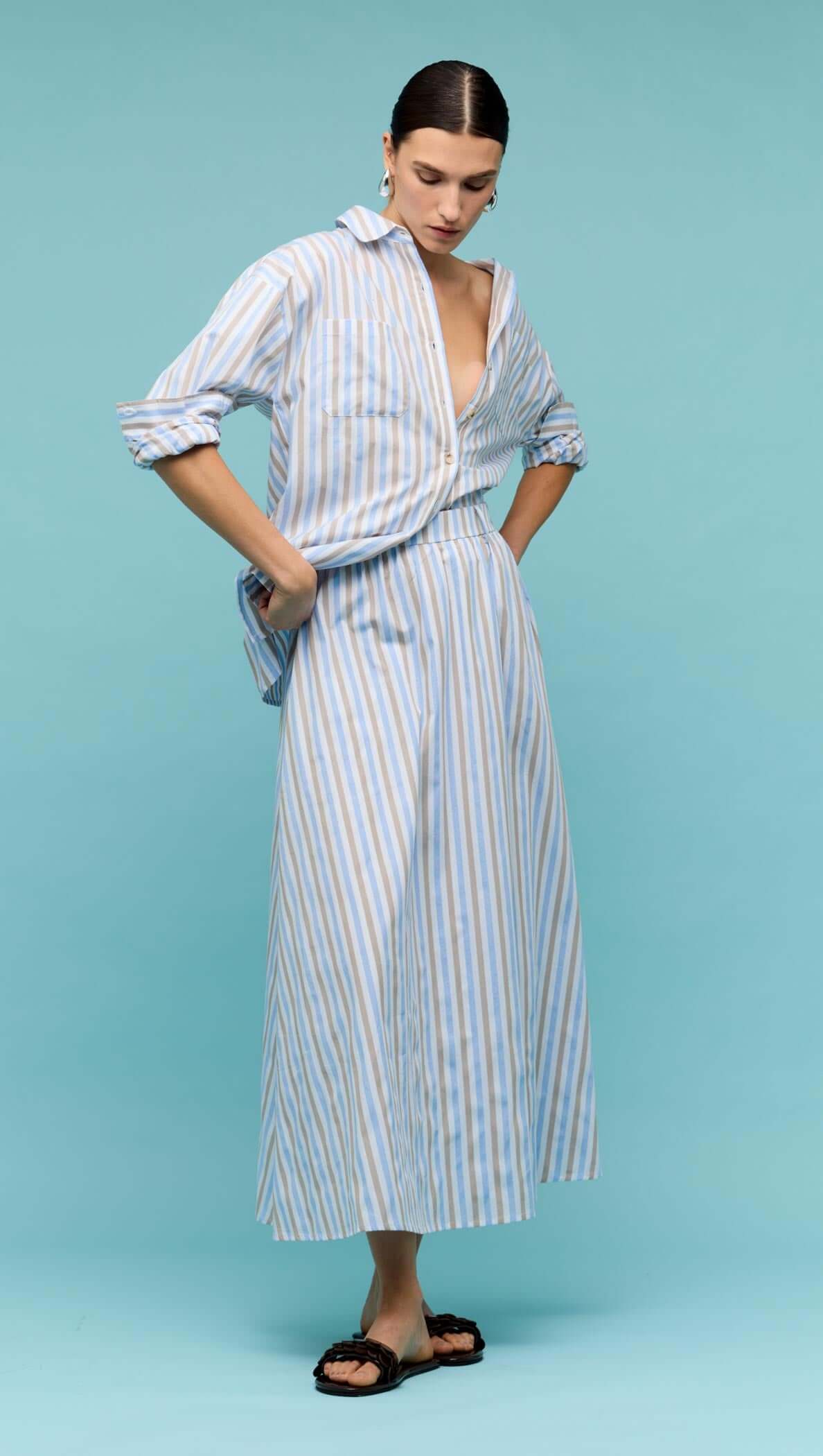 Model wearing a Blue Stripe Cotton A-Line Maxi Skirt paired with a matching striped shirt on a blue background.