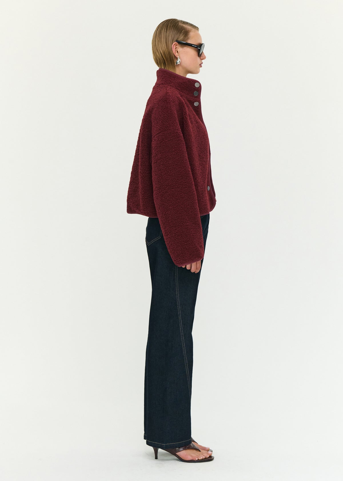 Side view of the Merlot High Neck Cropped Sherpa Jacket, showing a stand collar neckline and a snap button front closure.