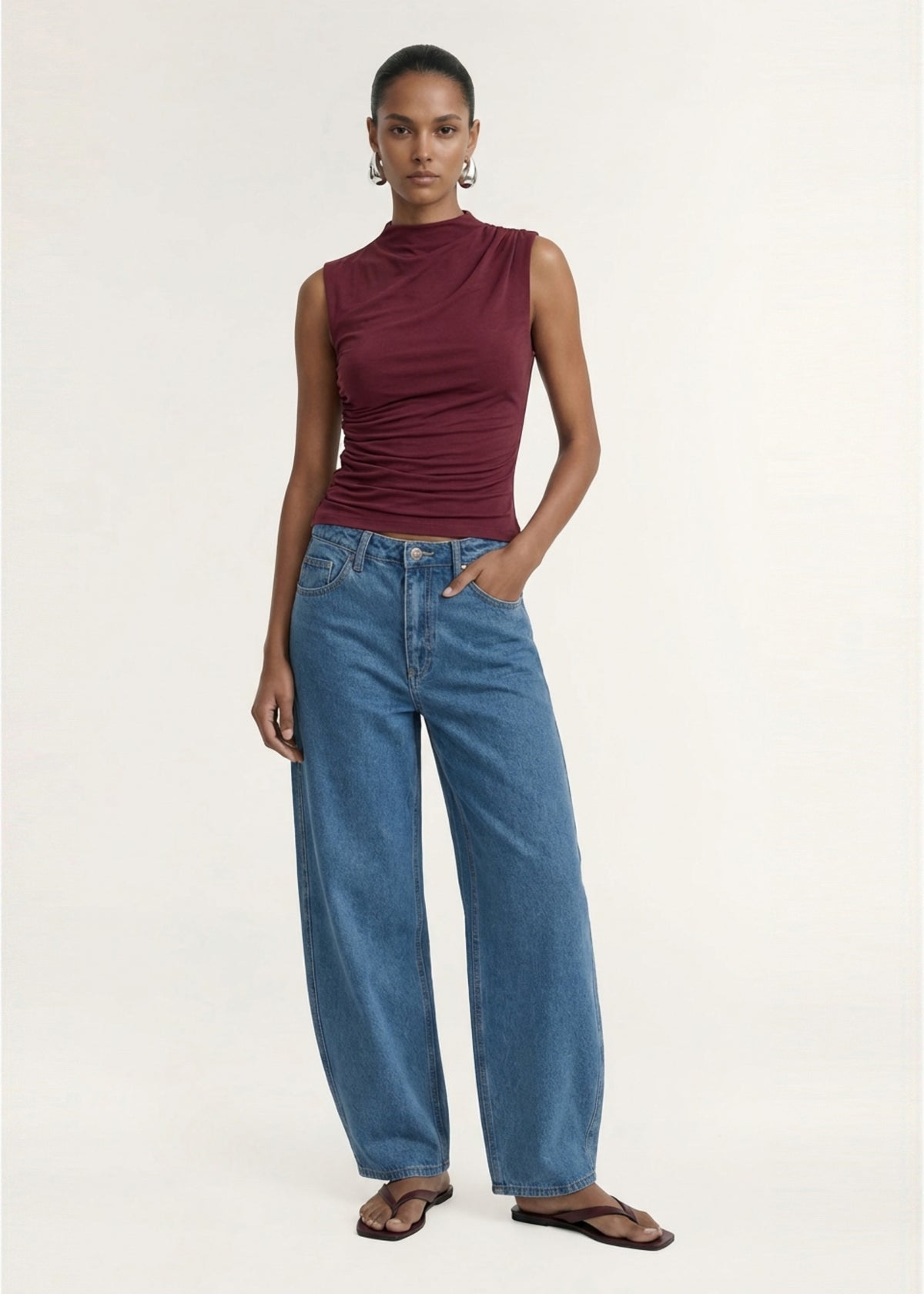 Model wearing Mid Blue Barrel Leg Denim Jeans with a mid-wash denim fabrication and a relaxed barrel-leg silhouette.