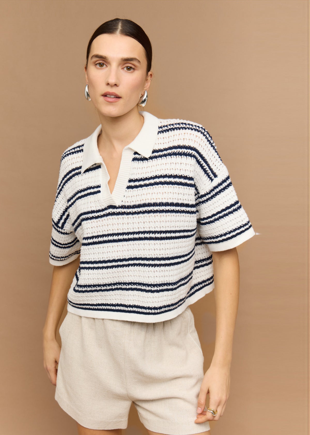 Close-up of the Navy and White Knit Polo Top, showing a short sleeves with drop shoulder and an open V-neckline.