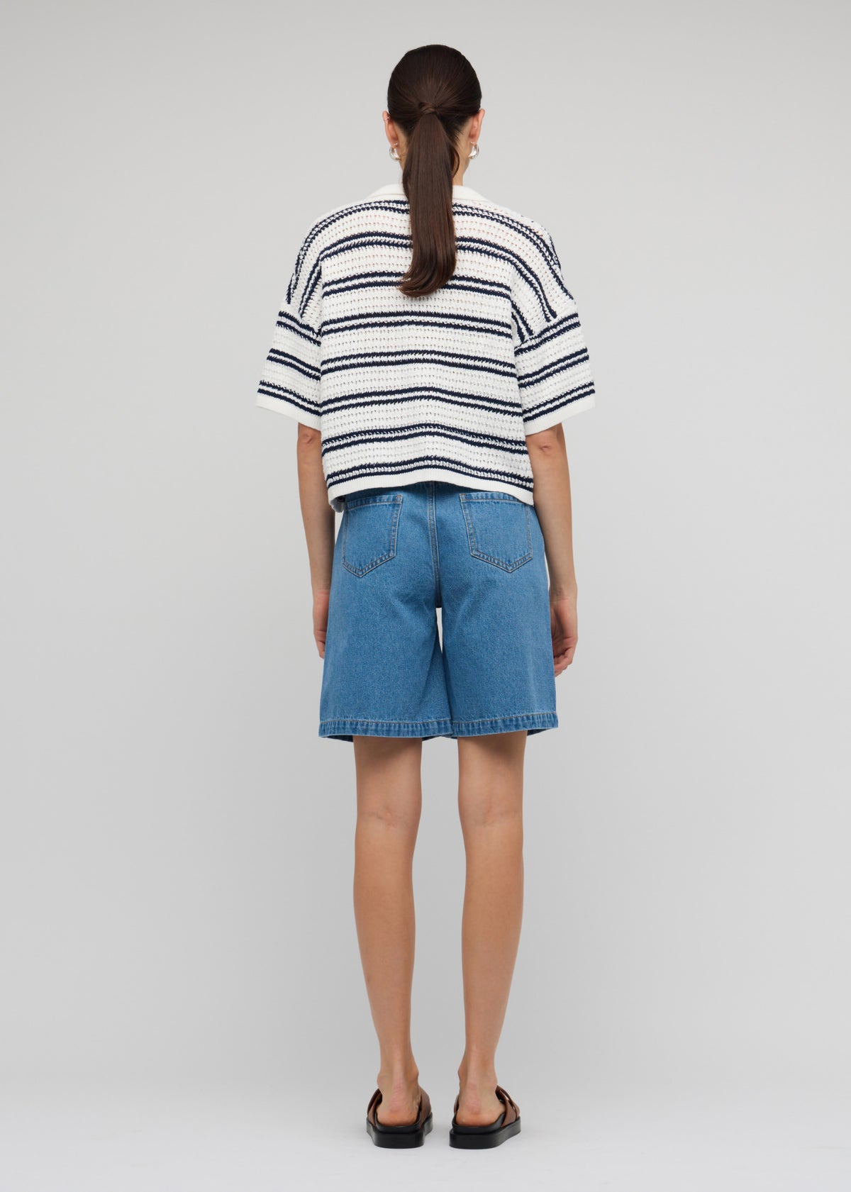 Back view of the Navy and White Knit Polo Top with an open V-neckline and a white base with navy stripe pattern.