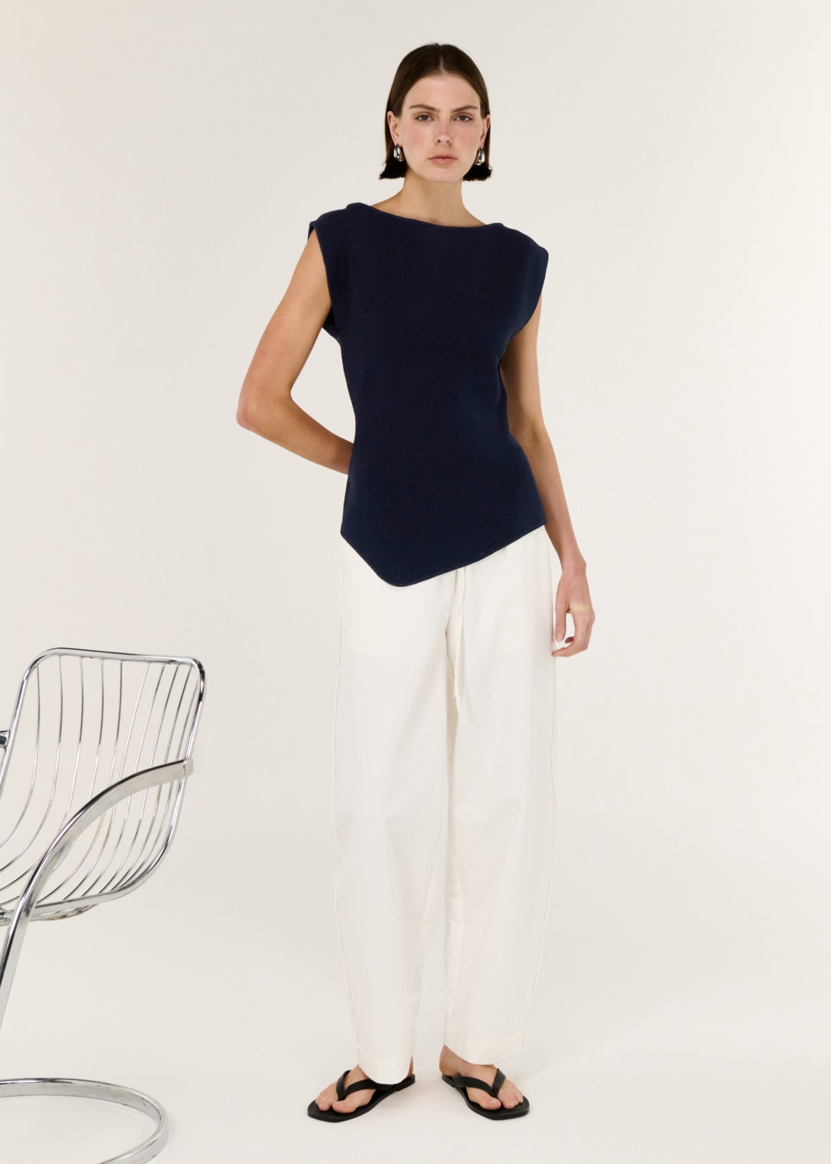 Model wearing Navy Boat Neck Knit Top, showing a soft stretch knit fabrication and an asymmetrical hemline.