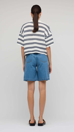 Back view of a woman wearing a Navy & White Knit Polo Top paired with denim shorts.