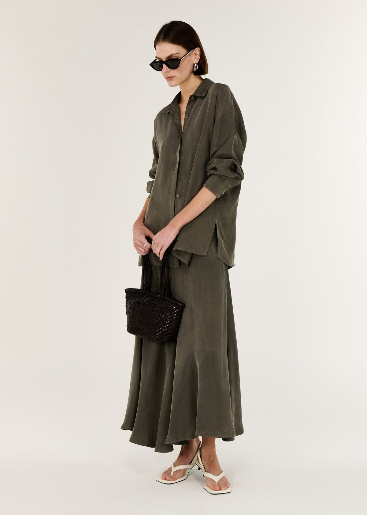 Model wearing Olive Cupro Asymmetrical Hem Maxi Skirt, showing a subtle sheen.