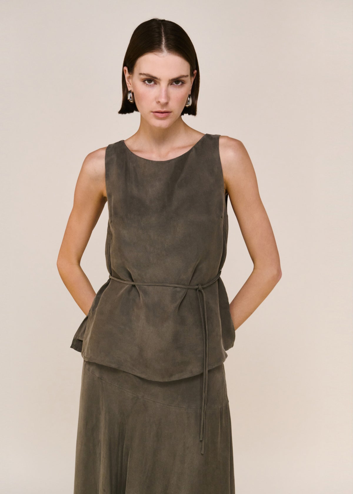 Close-up of the Olive Cupro Asymmetrical Hem Maxi Skirt, showing a high-waisted fit and a maxi length silhouette.