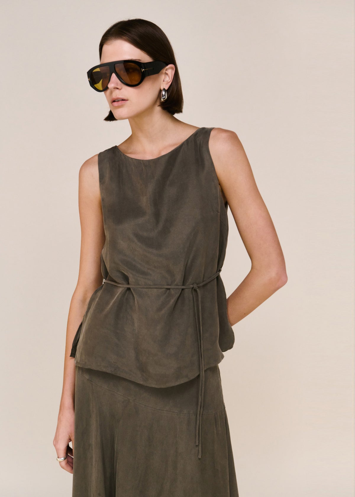 Close-up of the Olive Cupro Asymmetrical Hem Maxi Skirt, showing a maxi length silhouette and a high-waisted fit.