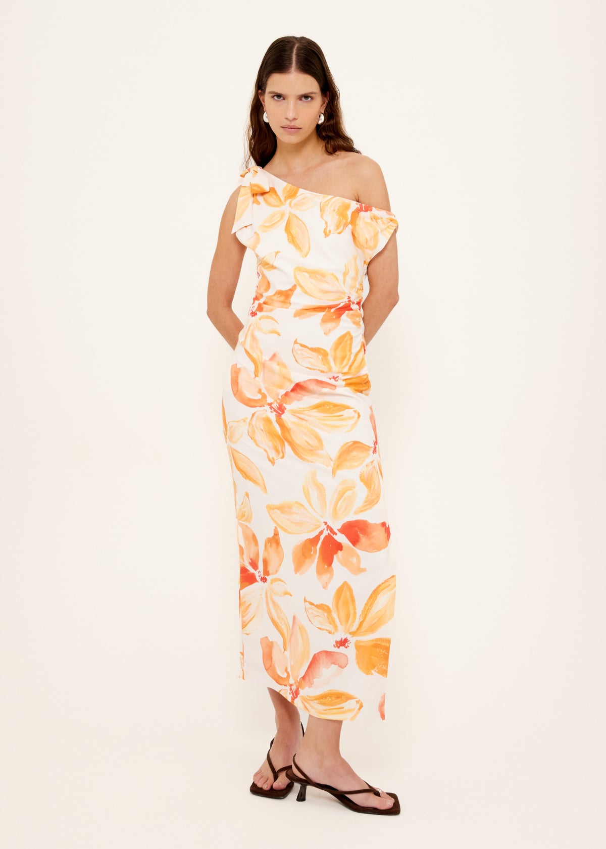 Model wearing Orange and White Floral Asymmetric Midi Dress, showing a fitted silhouette with side split and an invisible side zip closure.