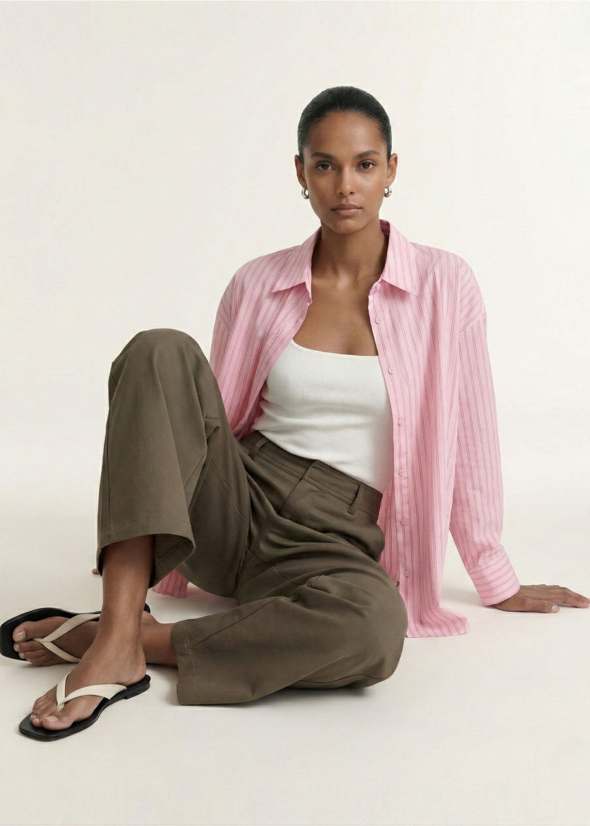 Model posed wearing Oversized Cotton Shirt with Back Button Detail, showing long sleeves with button cuffs and a curved hemline.