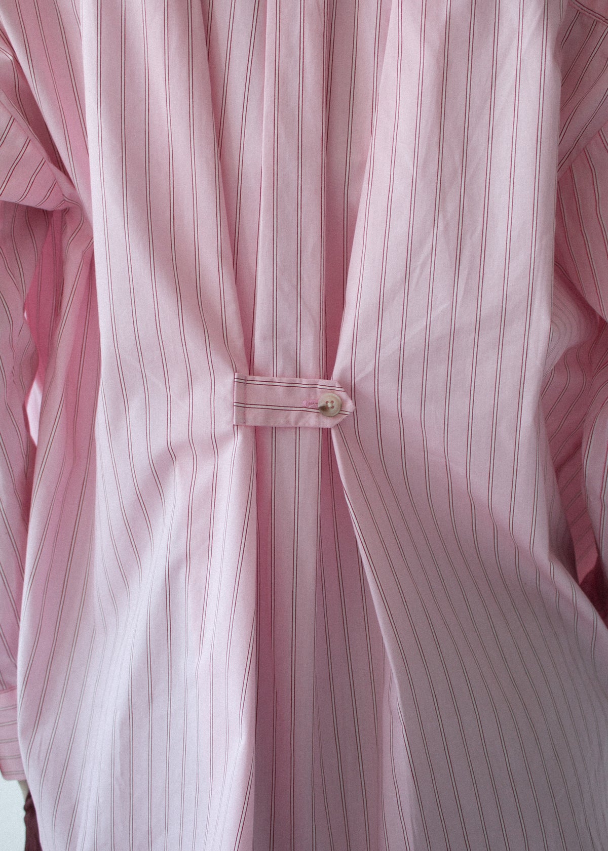 Close-up detail of the Oversized Cotton Shirt with Back Button Detail, showing back button tab.