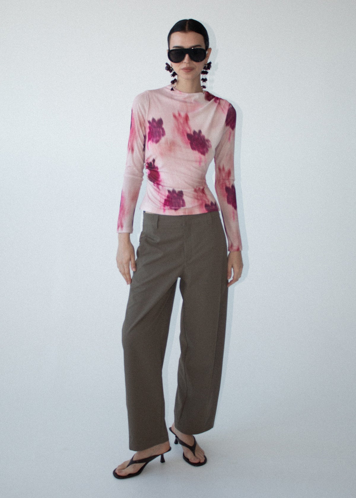 Model wearing Pink Floral Mesh Long Sleeve Top, showing long sleeves and a ruched waist detailing.