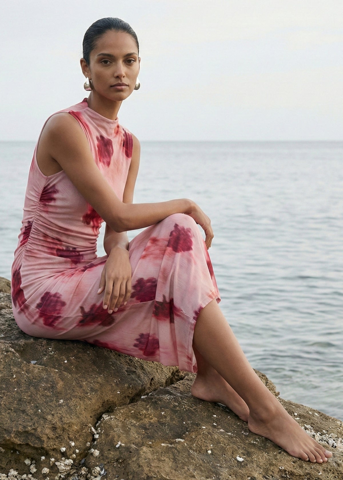 Model seated wearing Pink Floral Sleeveless Mesh Midi Dress with a fitted silhouette and a high neckline.